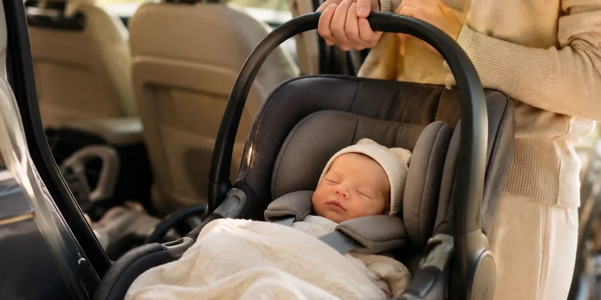 Nouveau-né installé dans une coque siège auto près d’une voiture